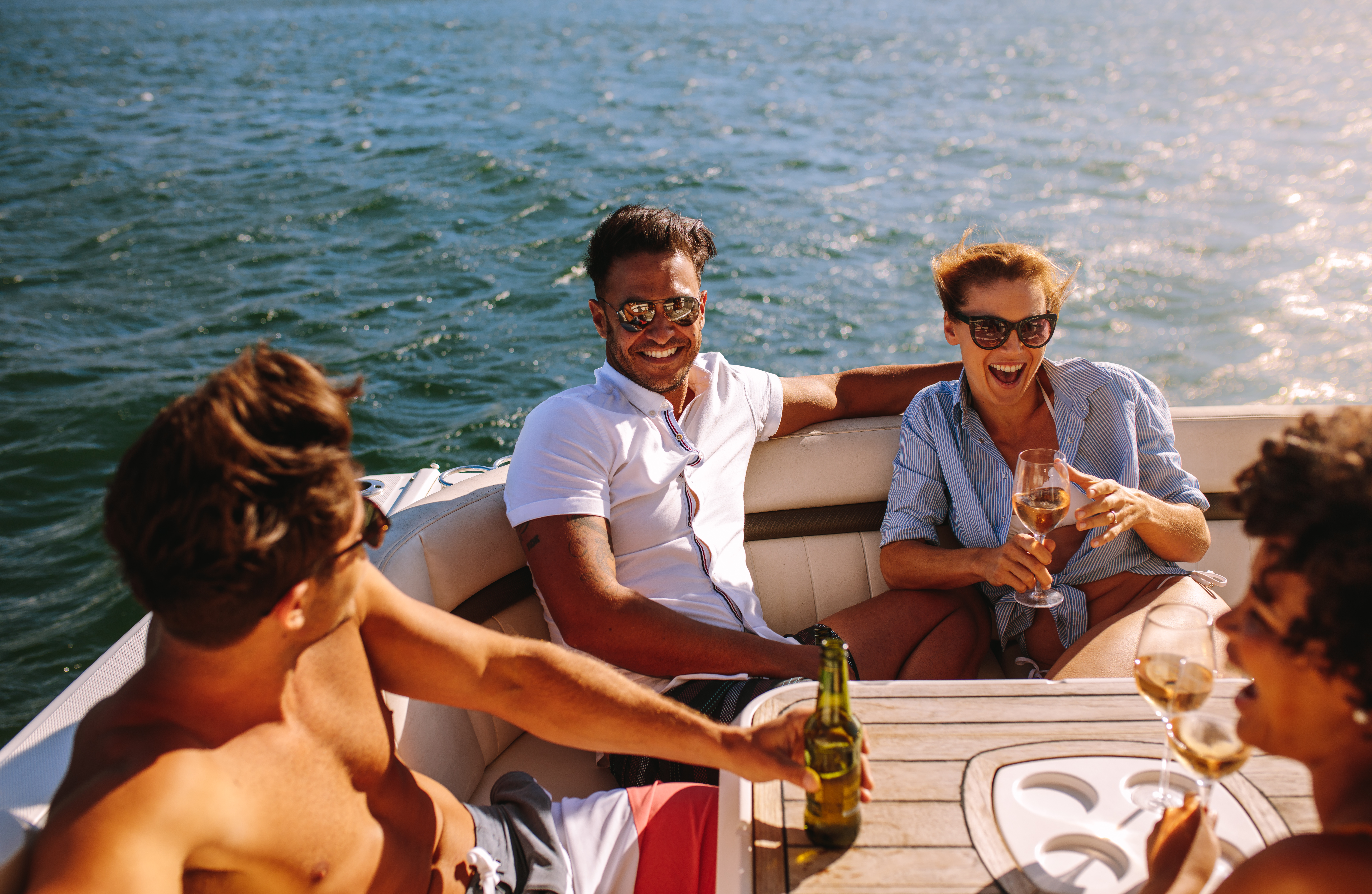 Four boys sitting on the deck of a boat and drinking their favourite beverages