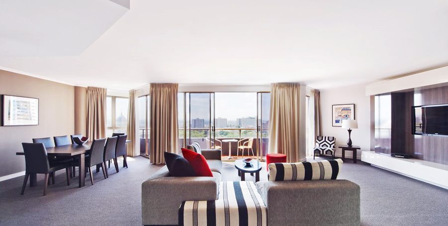Large apartment living and dining room with sofas opening onto a balcony