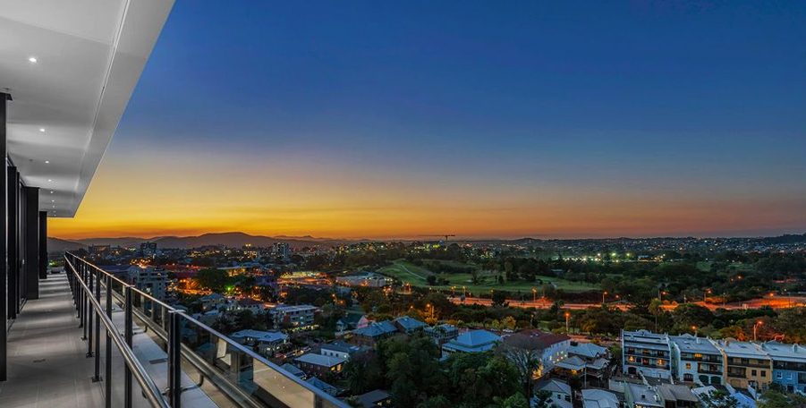 Long apartment balcony looking out over the suburbs at sunset