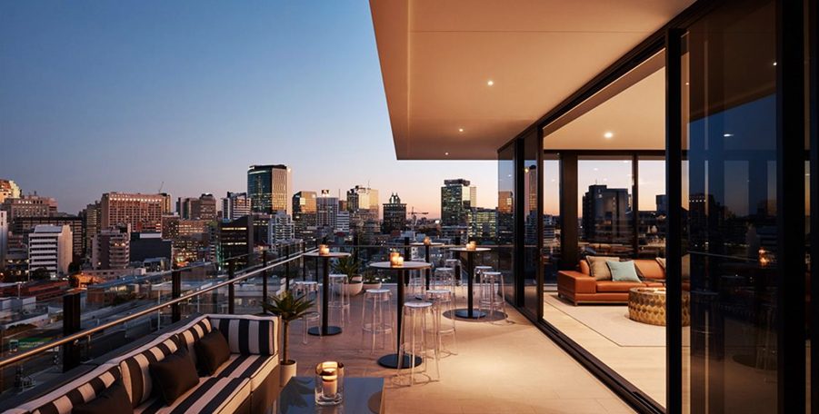 Penthouse deck with striped lounge seating, high tables and candles overlooking the city at dusk