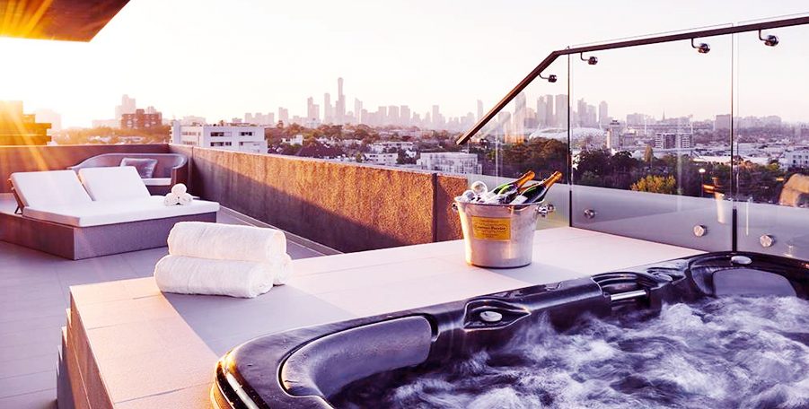 Rooftop spa with towels, sun lounges and champagne on ice, city skyline in the distance