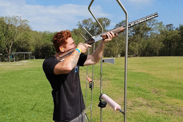 A bloke firing at a clay target on an open range