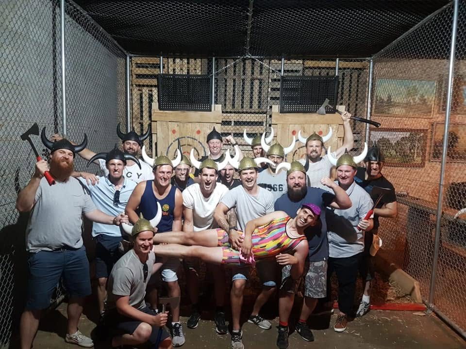 A bucks crew in Viking helmets packed into an axe-throwing cage