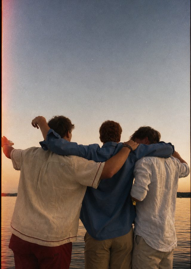 Mates with their arms around each other at sunset
