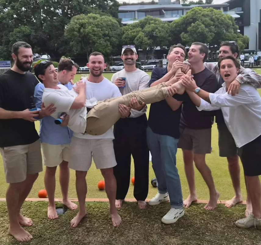 A group of mates holding up the buck at a lawn bowls venue
