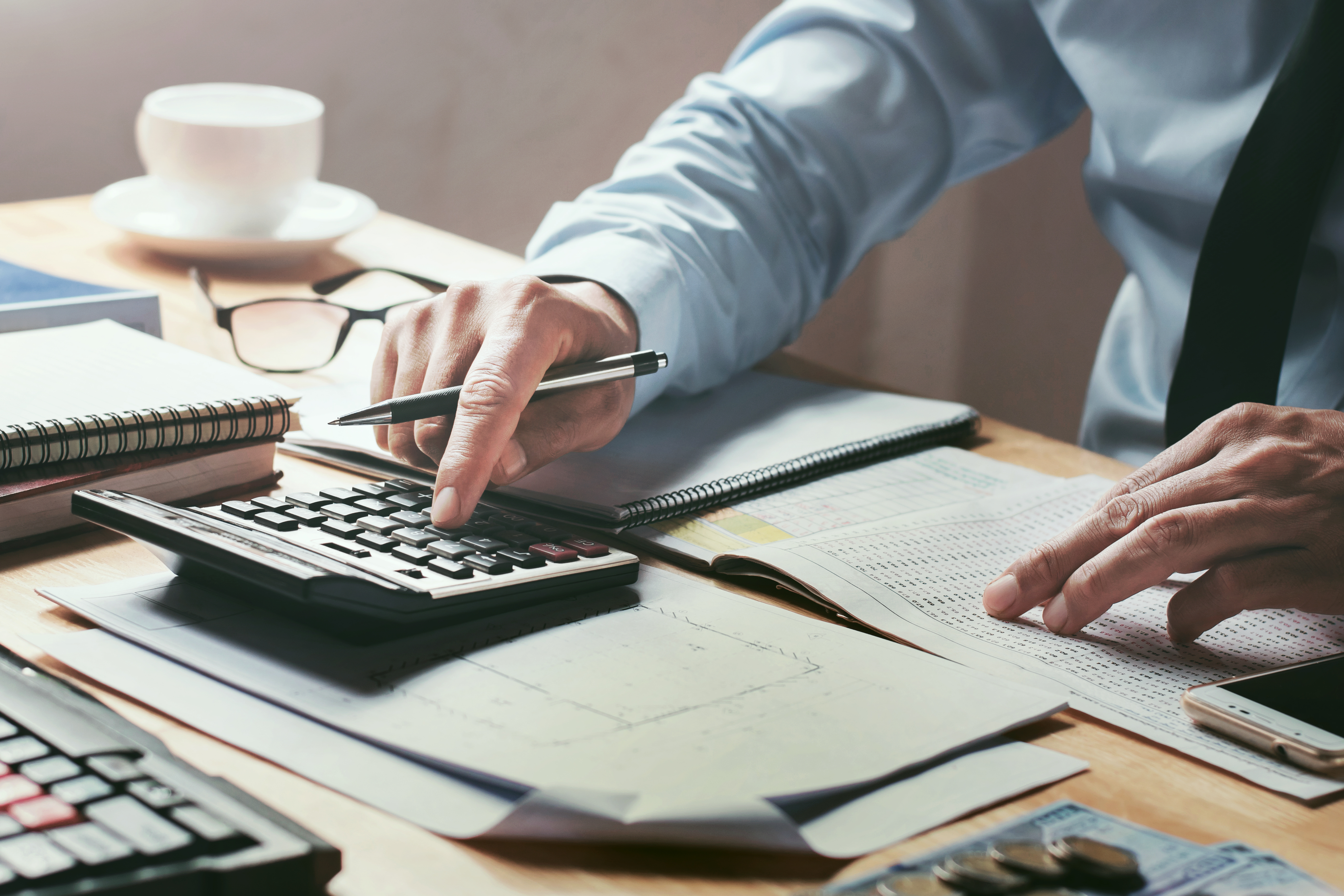 A well dressed man typing on a calculator