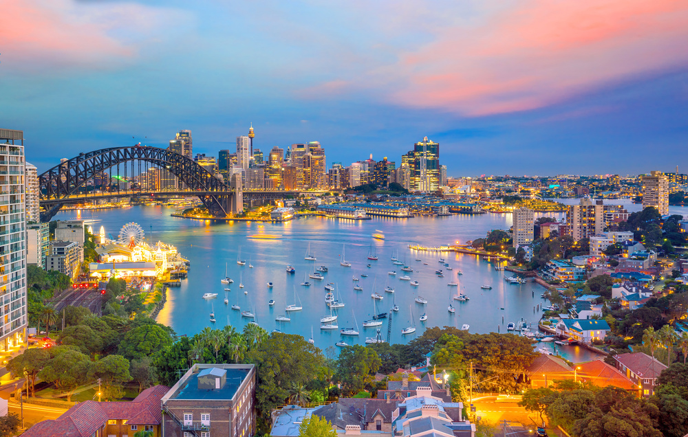 The Sydney Harbour Bridge and the CBD skyline at dusk, looking over Lavender Bay and Luna Park