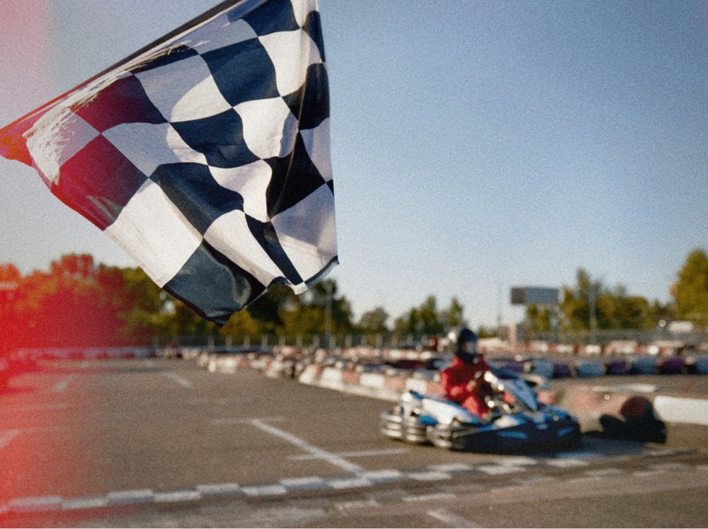 A chequered flag waving as a kart comes down the straight