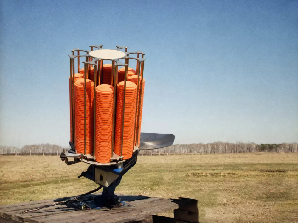 A clay target thrower loaded with orange clays on an open range