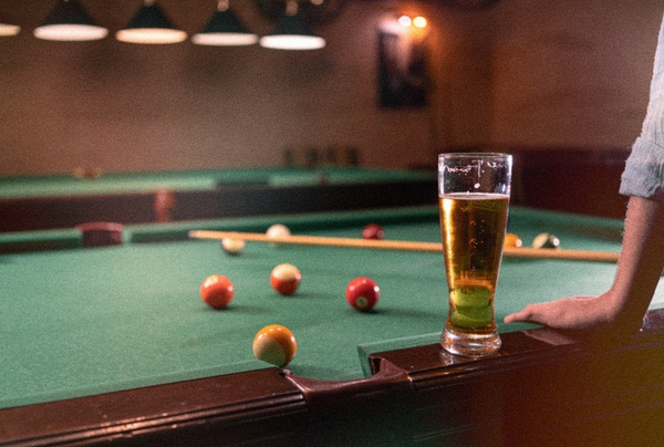 A pint of beer on the edge of a pool table mid-game