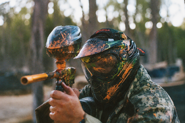 A paintballer in a camo mask aiming his marker