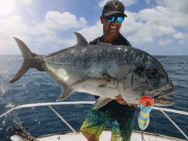 A bloke on a boat holding up a big fish
