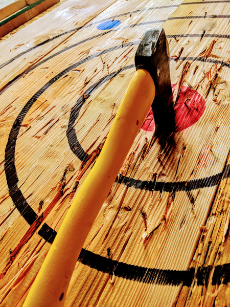 An axe stuck in the centre of a timber target