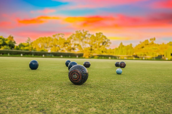 Lawn bowls on the green under a sunset sky
