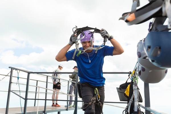 A bloke in a harness and helmet on a high platform