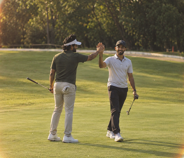 Two golfers high-fiving on the fairway