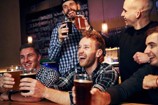 A crew of blokes laughing over beers at the bar