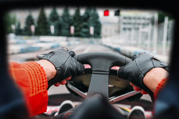 Gloved hands on a go-kart steering wheel at the start line