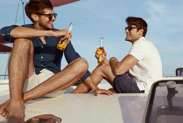 Two blokes on a boat deck in the sun, beers in hand