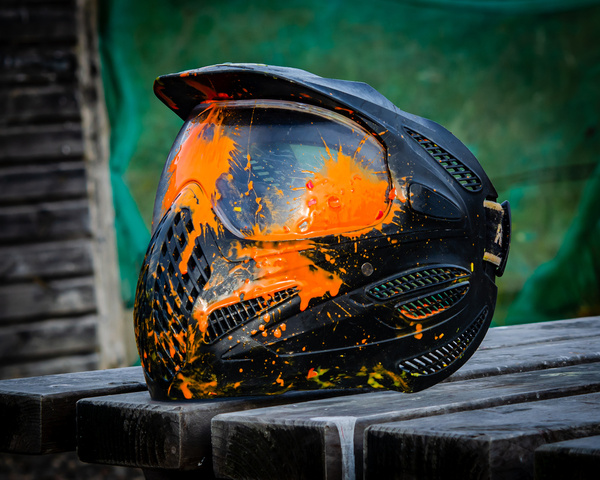 A paint-splattered paintball mask on a ledge