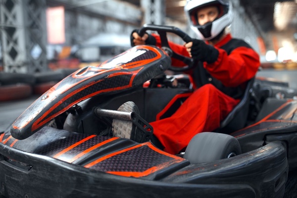 A driver in a red suit in a go-kart