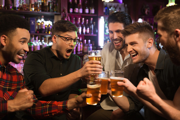A crew cheering with beers at a busy bar