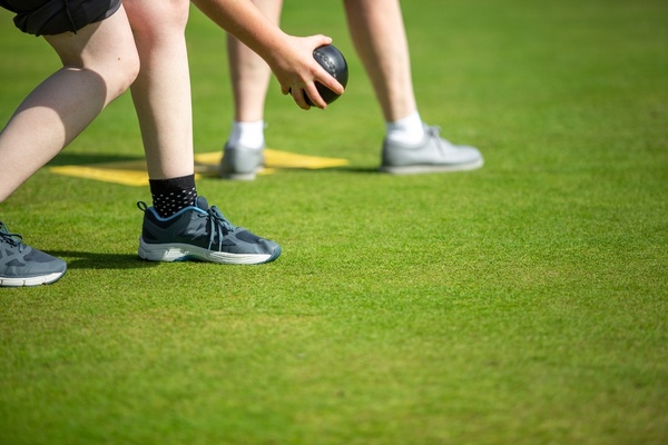 A barefoot bowler sending one down the green