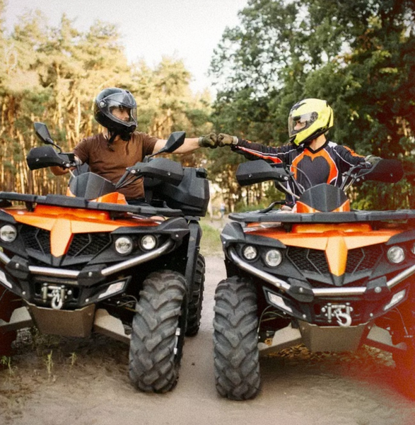 Two riders on quad bikes bumping fists on a bush track