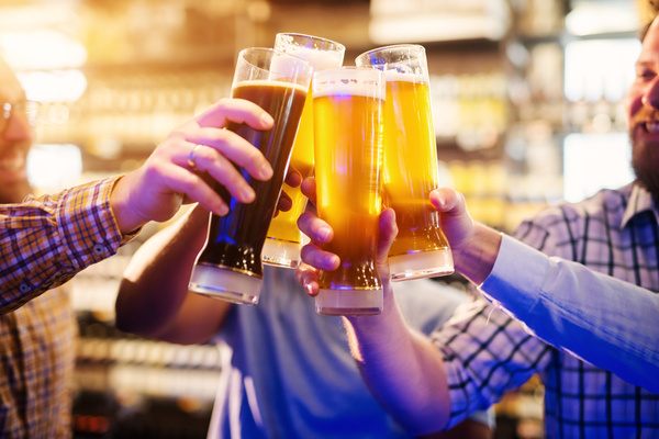 Mates clinking pints at the bar