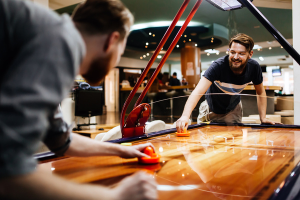 Two mates going head to head at air hockey