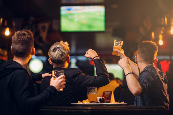 Mates with beers watching the game on a big screen