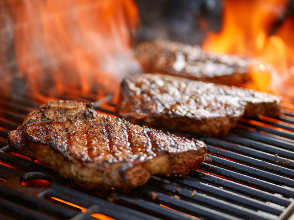 Steaks searing on a flaming grill