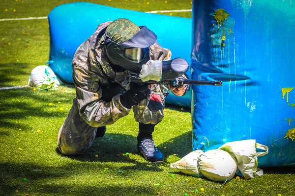 A paintballer crouched behind an inflatable bunker