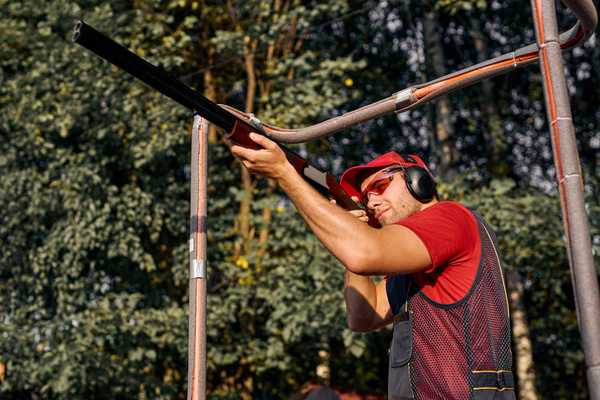 A shooter in ear muffs firing among the trees