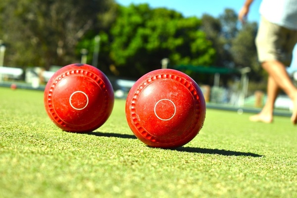 Two red lawn bowls on a sunny green