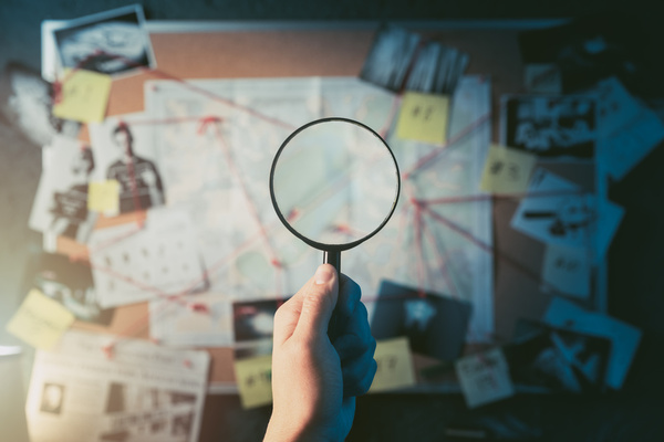 A magnifying glass over a wall of clues