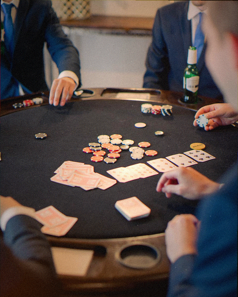 Blokes in suits playing cards around a poker table