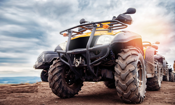 A quad bike parked on a sandy track under a big sky