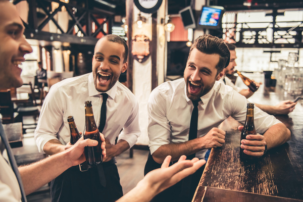 Mates in shirts and ties laughing with beers