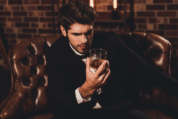 A man in a suit holding a glass of whisky