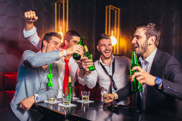 Blokes in suits celebrating with beers at a bar
