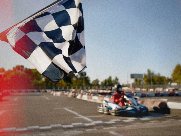 A chequered flag waving as a go-kart comes down the straight