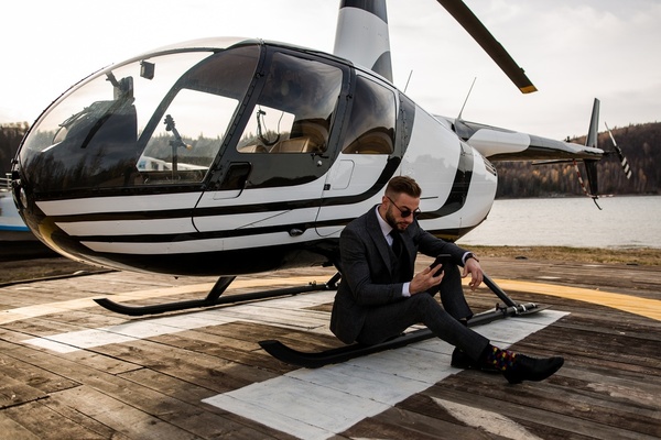 A man in a suit beside a helicopter on the pad