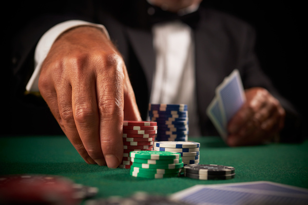 A man in a dinner suit pushing chips across a poker table