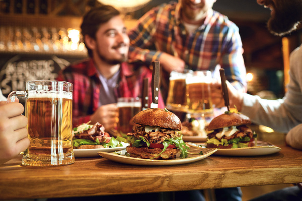 A crew around a table of burgers and beers