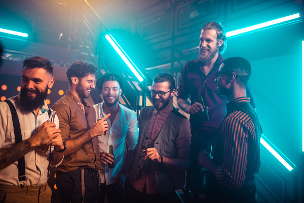 A crew of blokes with drinks under neon lights