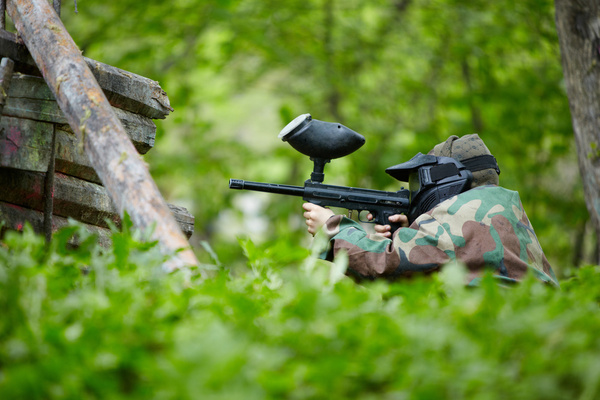 A paintballer aiming from the grass