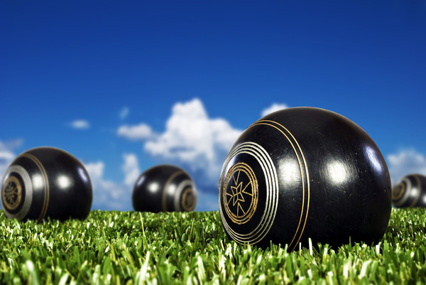 Black lawn bowls on the green under a blue sky