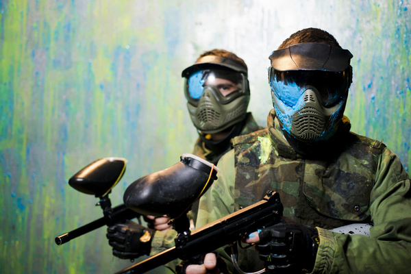 Two paintballers in masks holding their markers