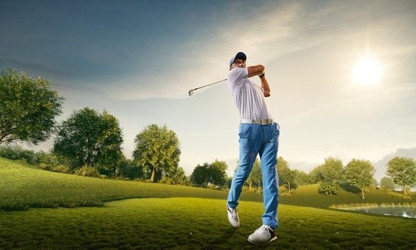 A golfer mid-swing under a bright sky